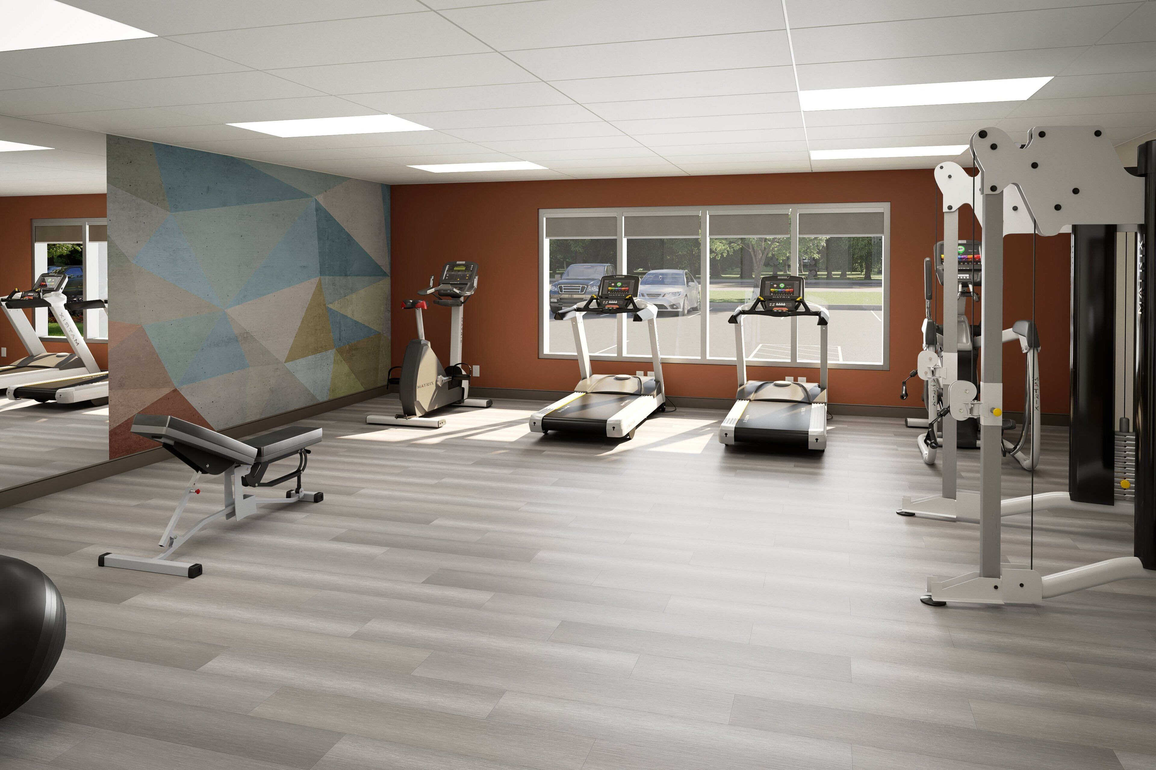A gym with treadmills, elliptical machines, and a wall-mounted exercise station.