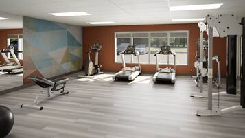 A gym with treadmills, elliptical machines, and a wall-mounted exercise station.