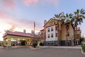 A hotel with a covered parking area, palm trees, and a sunset sky. - Homewood Suites by Hilton Phoenix/Chandler (Chandler)