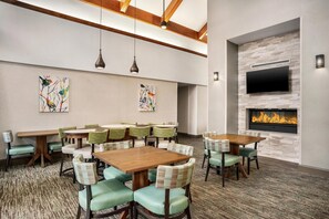 A conference room with tables and chairs, a fireplace, and artwork on the walls. - Homewood Suites by Hilton Phoenix/Chandler (Chandler)