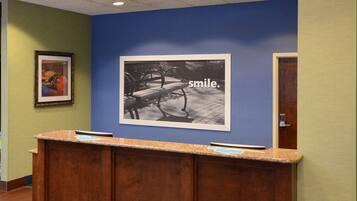 A reception desk with a framed picture of a bench and a sign that says "smile."