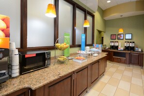 A breakfast bar with a coffee maker, microwave, and fruit bowl.