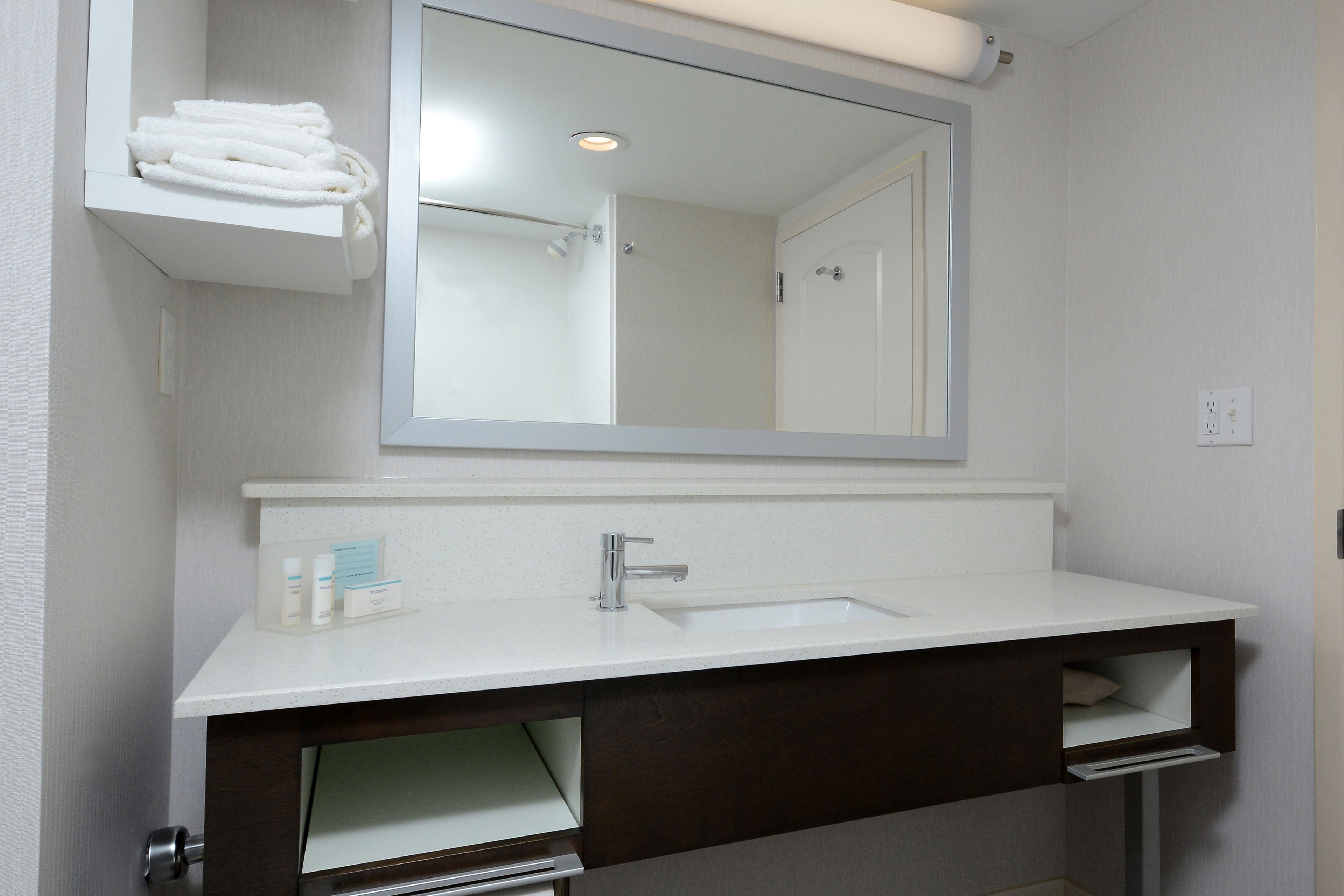A bathroom with a white sink, dark vanity, and a mirror above the sink.