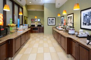 Cocina de hotel con encimeras de granito, armarios de madera e iluminación colgante.