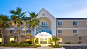 A hotel with a modern design, featuring a prominent entrance with a curved awning and palm trees in the foreground. - Sonesta Simply Suites Jacksonville (Jacksonville)