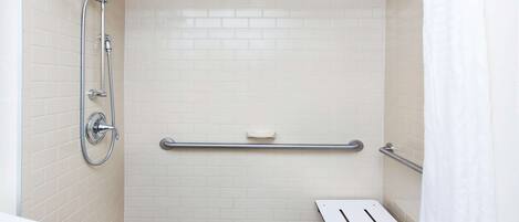 A bathroom with a shower, a toilet, and a grab bar.