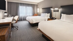 A hotel room with two beds, a desk, a chair, a TV, and a large window with curtains. - Courtyard by Marriott Burlington (Burlington)