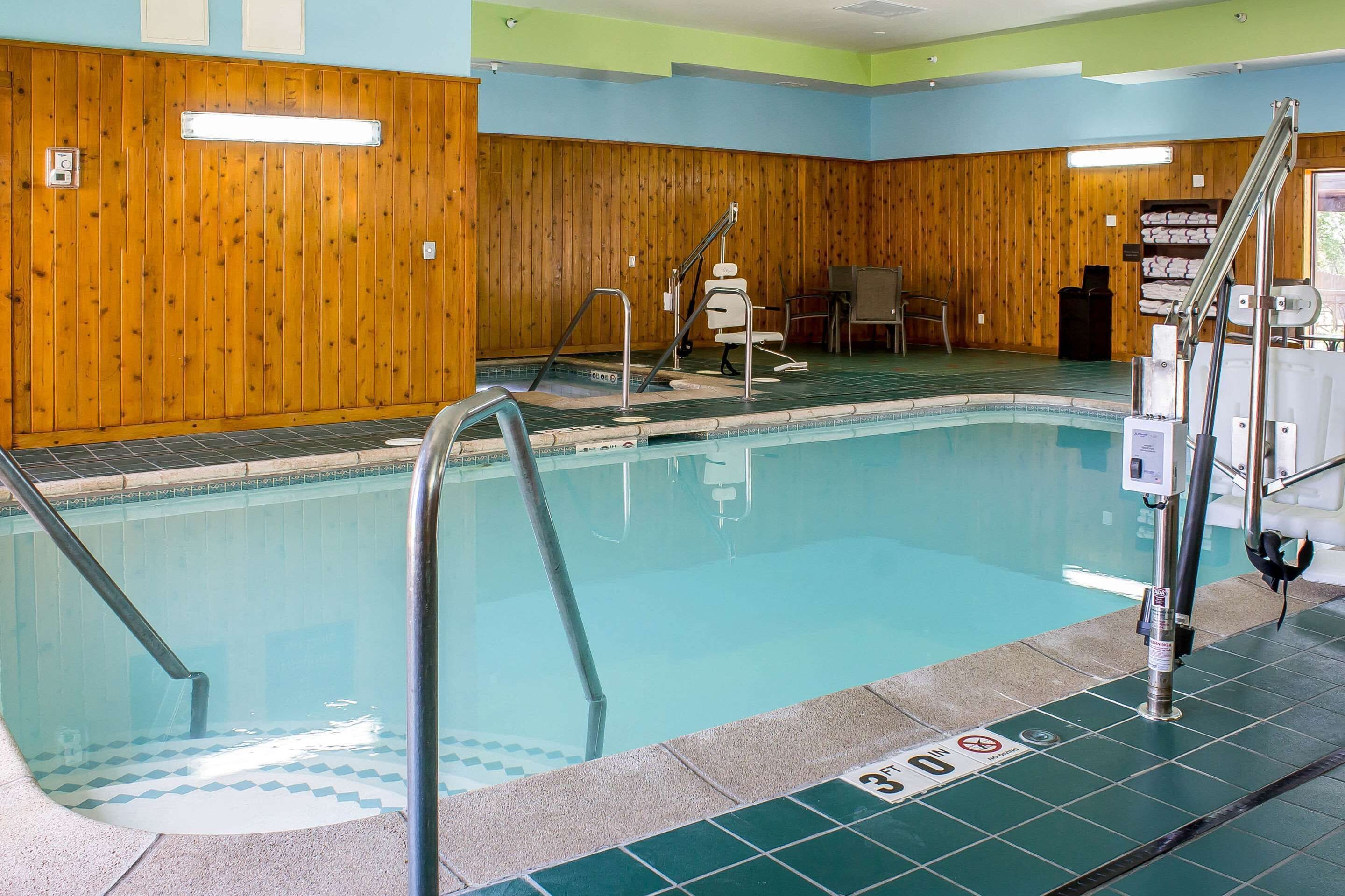 Ein Schwimmbecken mit Holzwänden, einem Rettungsschwimmerstuhl und einer Poolleiter.