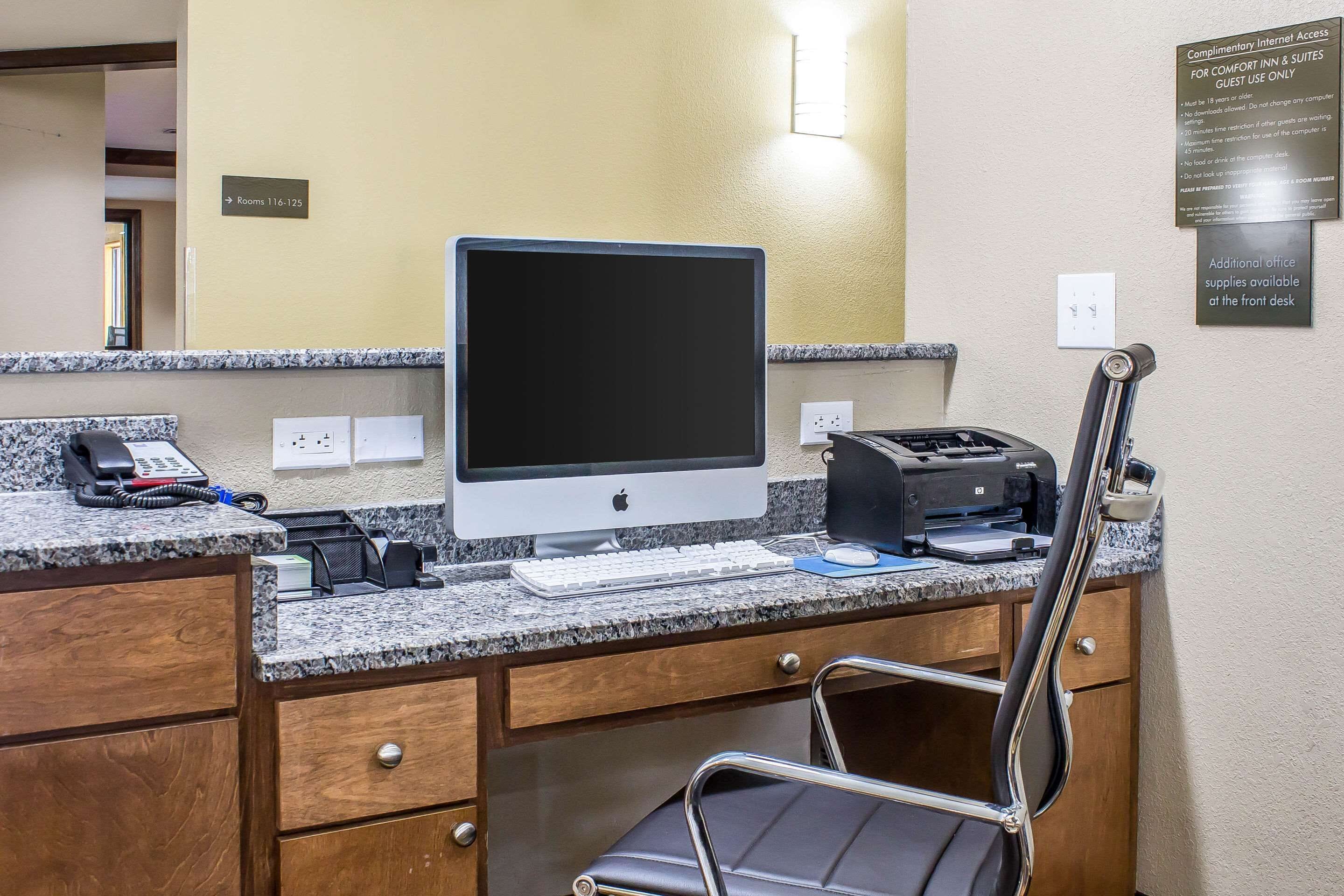 Un comptoir de réception d’hôtel équipé d’un ordinateur, d’une imprimante, d’un téléphone et d’une chaise.