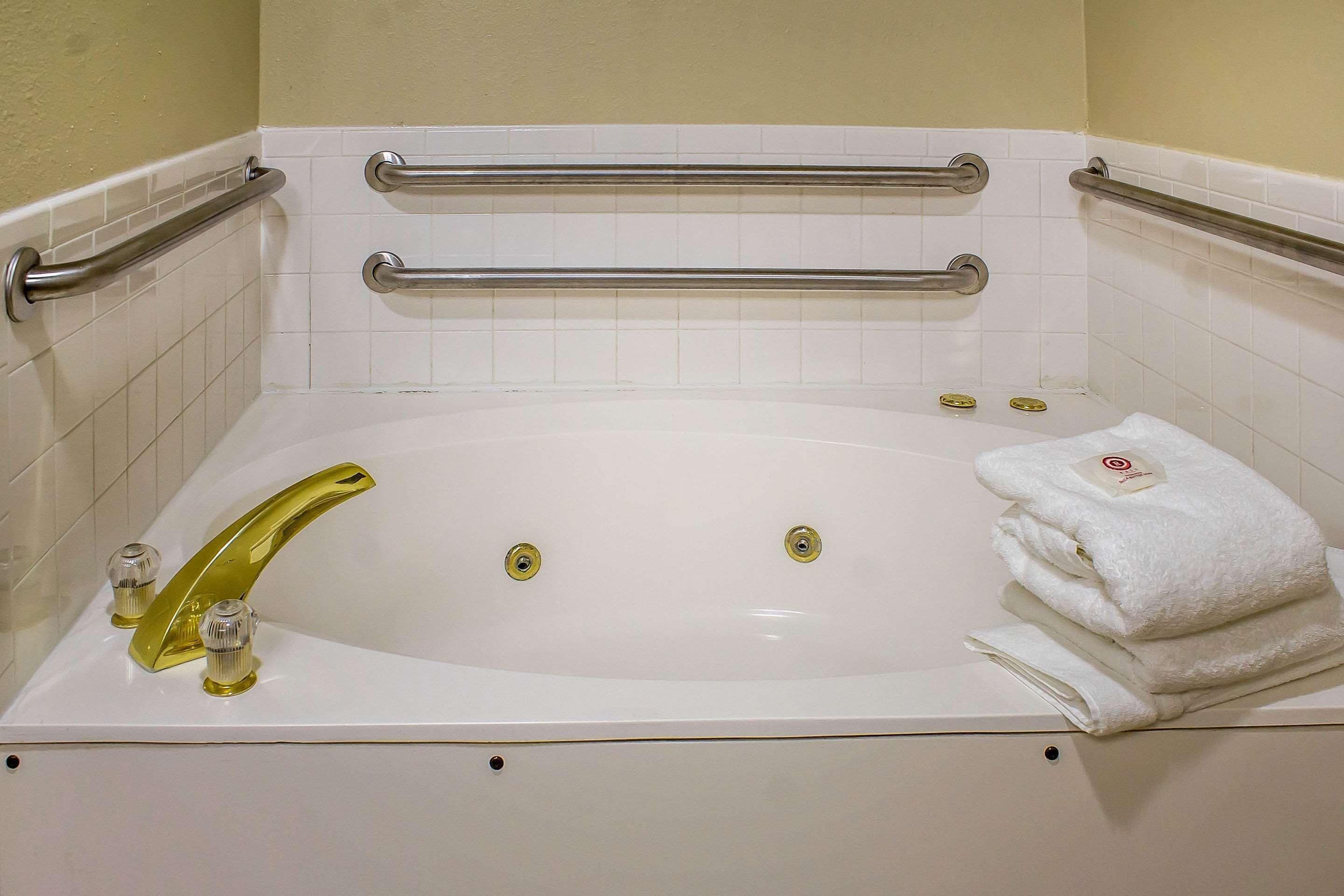 Une baignoire blanche avec deux robinets, une serviette et une barre d’appui.