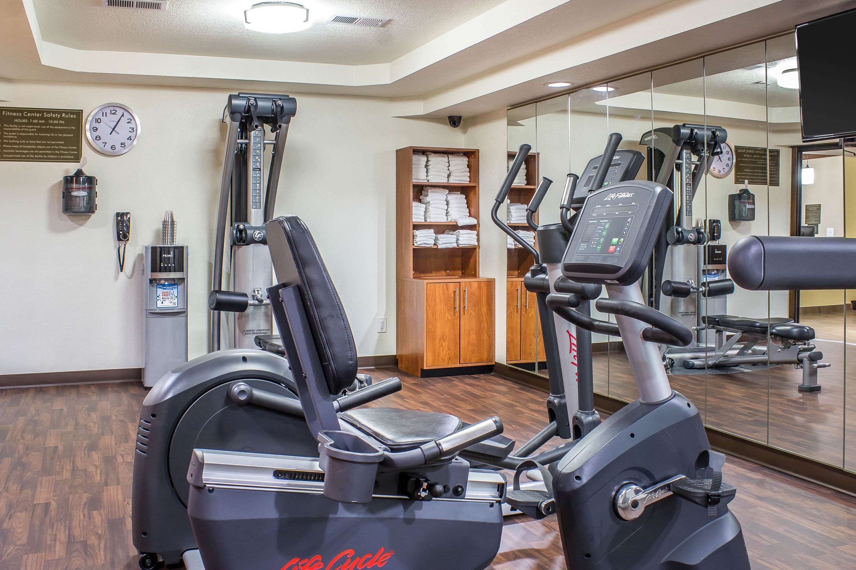 A gym with cardio equipment, a clock, and a mirror.