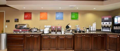A hotel kitchen with wooden cabinets, granite countertops, and various appliances including a coffee machine and a rice cooker.