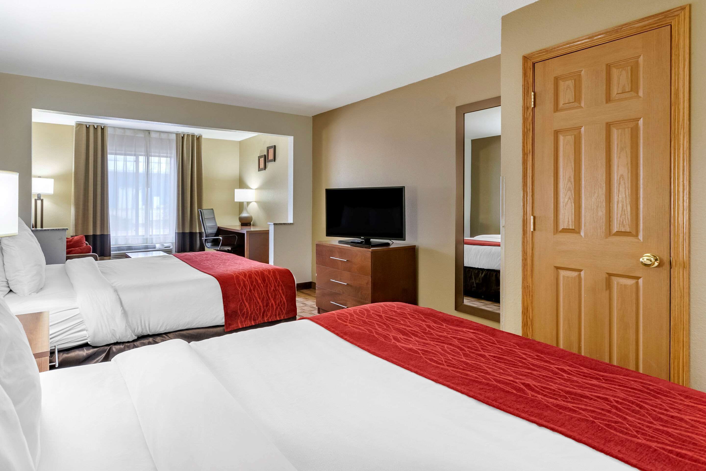Une chambre d’hôtel avec deux lits, une télévision, un bureau et une armoire.
