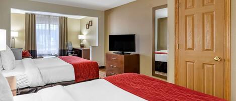 Une chambre d’hôtel avec deux lits, une télévision, un bureau et une armoire.