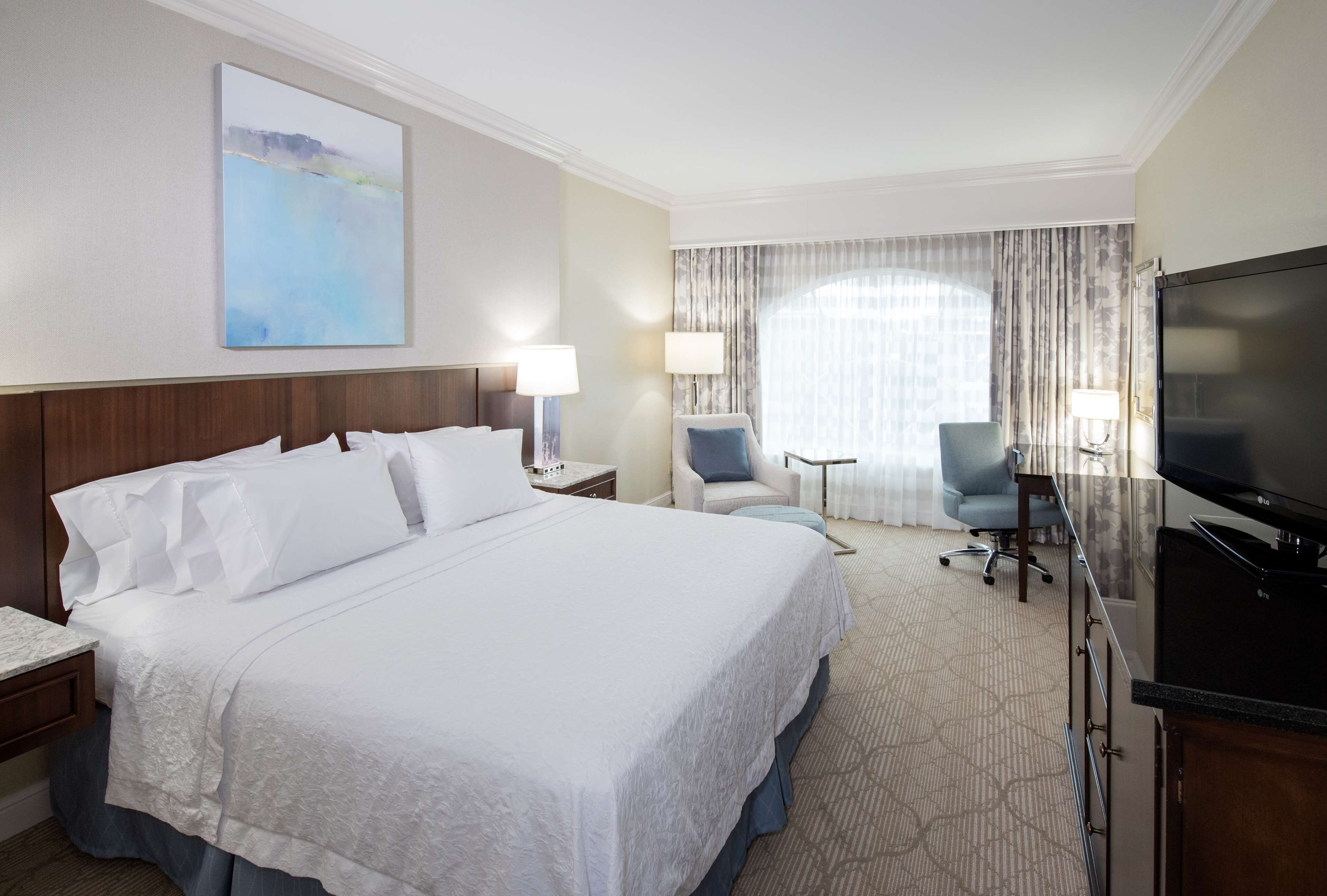 Une chambre d’hôtel avec un grand lit, une télévision, un bureau et une chaise.