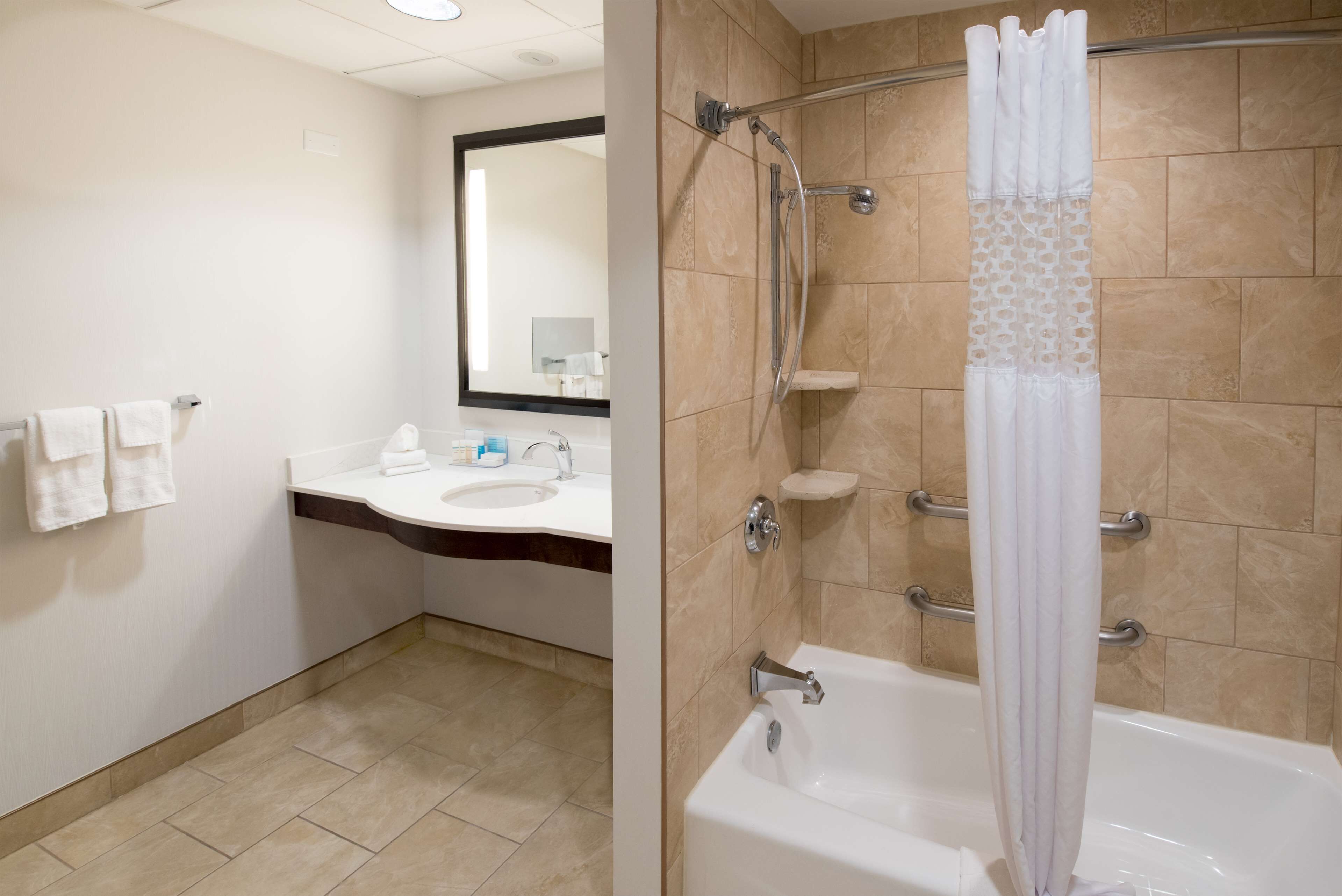 Une salle de bain équipée d’un lavabo, d’un miroir et d’un espace douche.