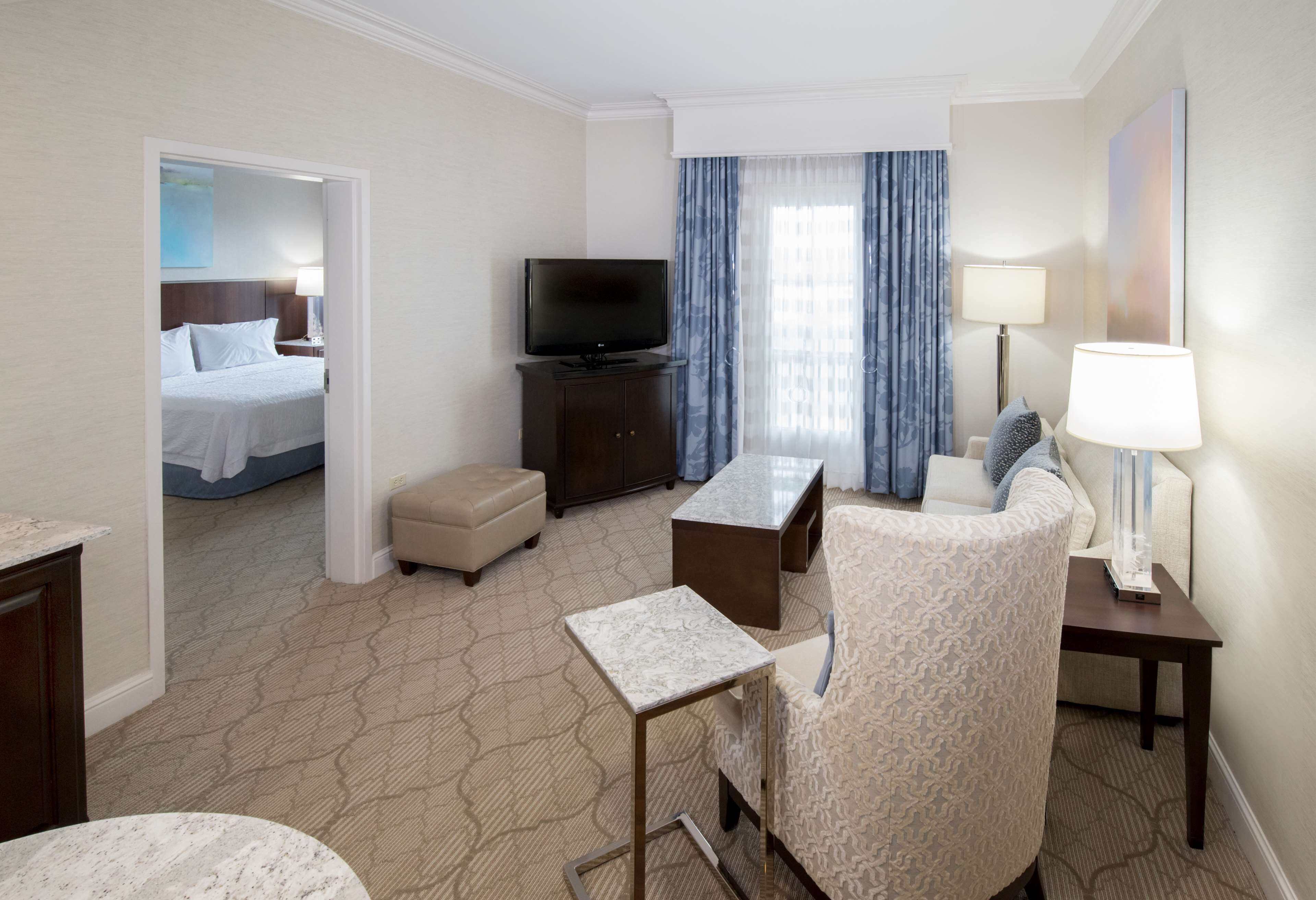 A hotel room with a bed, a TV, a sofa, a coffee table, and a lamp.