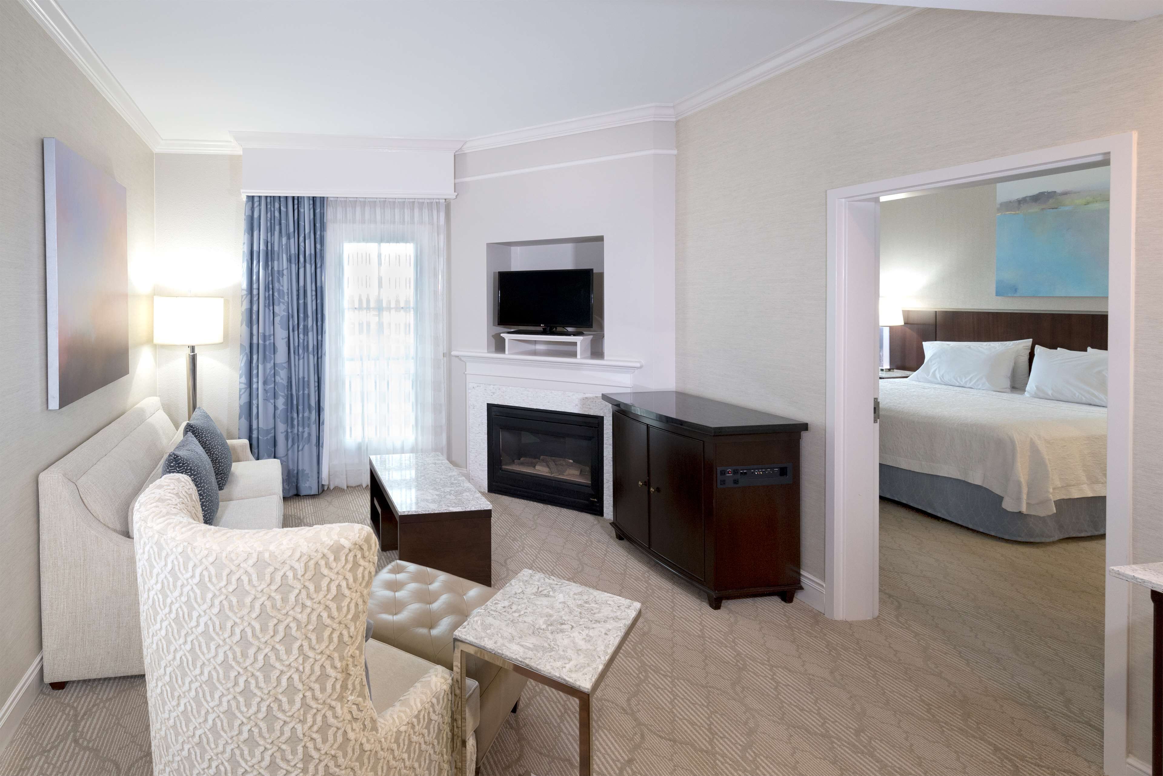 Une chambre d’hôtel avec un canapé, une petite table, une télévision, une cheminée et un lit.