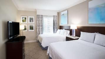 A hotel room with two beds, a TV, and a desk with a lamp.