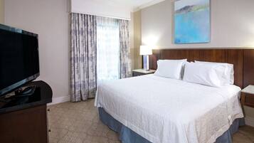 A hotel room with a large bed, a flat-screen TV, a desk, and a painting on the wall.