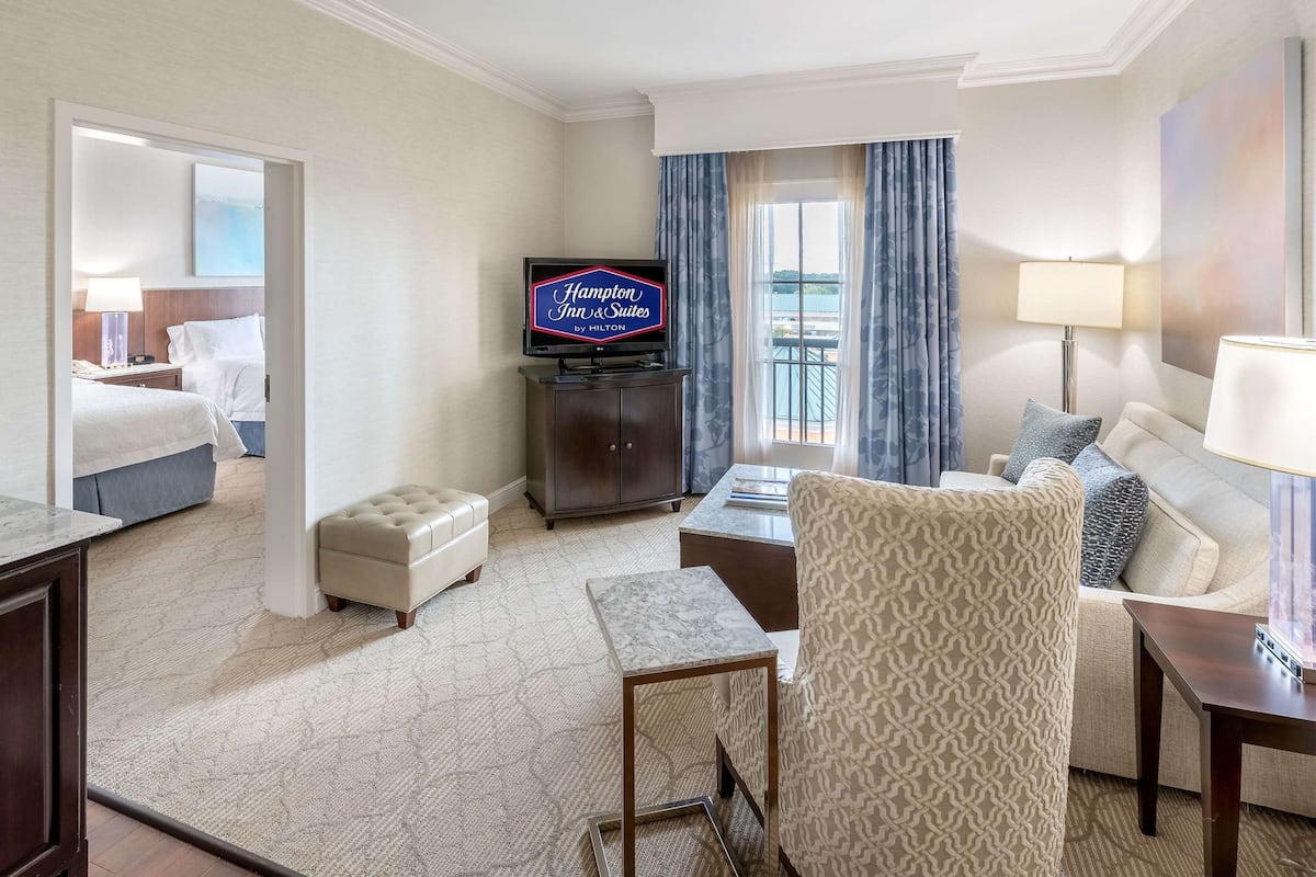 A hotel room with a bed, a desk, a television, a chair, a sofa, and a view of the outdoors.