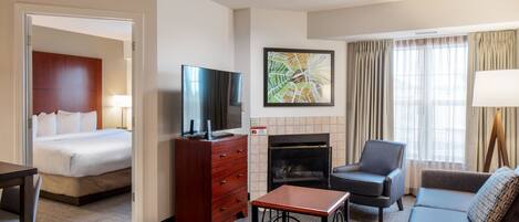 Habitación de hotel con cama, televisor, chimenea, sofá y escritorio.