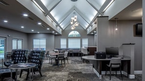 A modern hotel lobby with a high ceiling, skylights, and a mix of seating areas including tables and chairs. - Residence Inn by Marriott Little Rock (Little Rock)