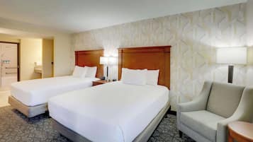 A hotel room with two beds, a sofa, and a lamp.