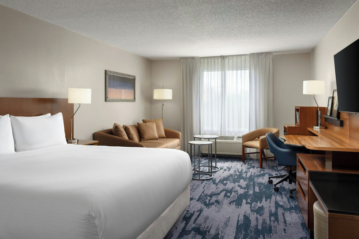 Ein Hotelzimmer mit einem großen Bett, einer Couch, einem Schreibtisch und einem Fernseher.