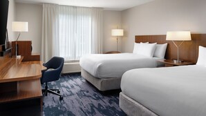 Ett hotellrum med två sängar, ett skrivbord och två lampor.