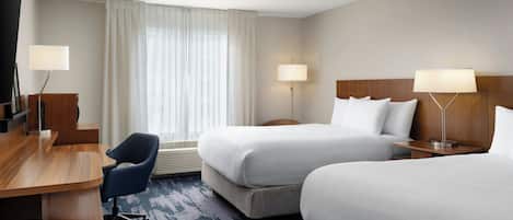 Ett hotellrum med två sängar, ett skrivbord och en stol.