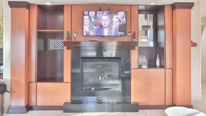 A modern living room with a fireplace, a flat-screen TV mounted above it, and a small white table. - Comfort Inn & Suites Houston North - Spring (Houston)