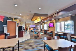 A hotel lobby with a reception desk, seating area, and a television screen.