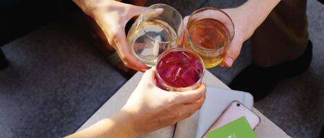 A person holding a smartphone and a green card, with a glass of iced tea and a glass of beer on a table.