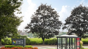 Un letrero de Hyatt Place, una parada de autobús y un césped bien cuidado con árboles.