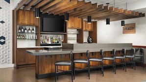 Eine moderne Bar mit Holzakzenten, einer langen Theke und mehreren Barhocker.