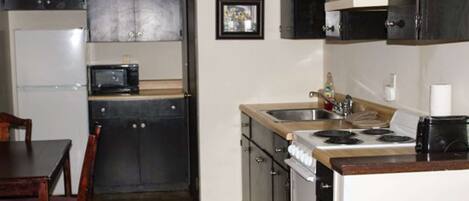 A compact kitchen with dark cabinets, a microwave, a sink, and a stove.