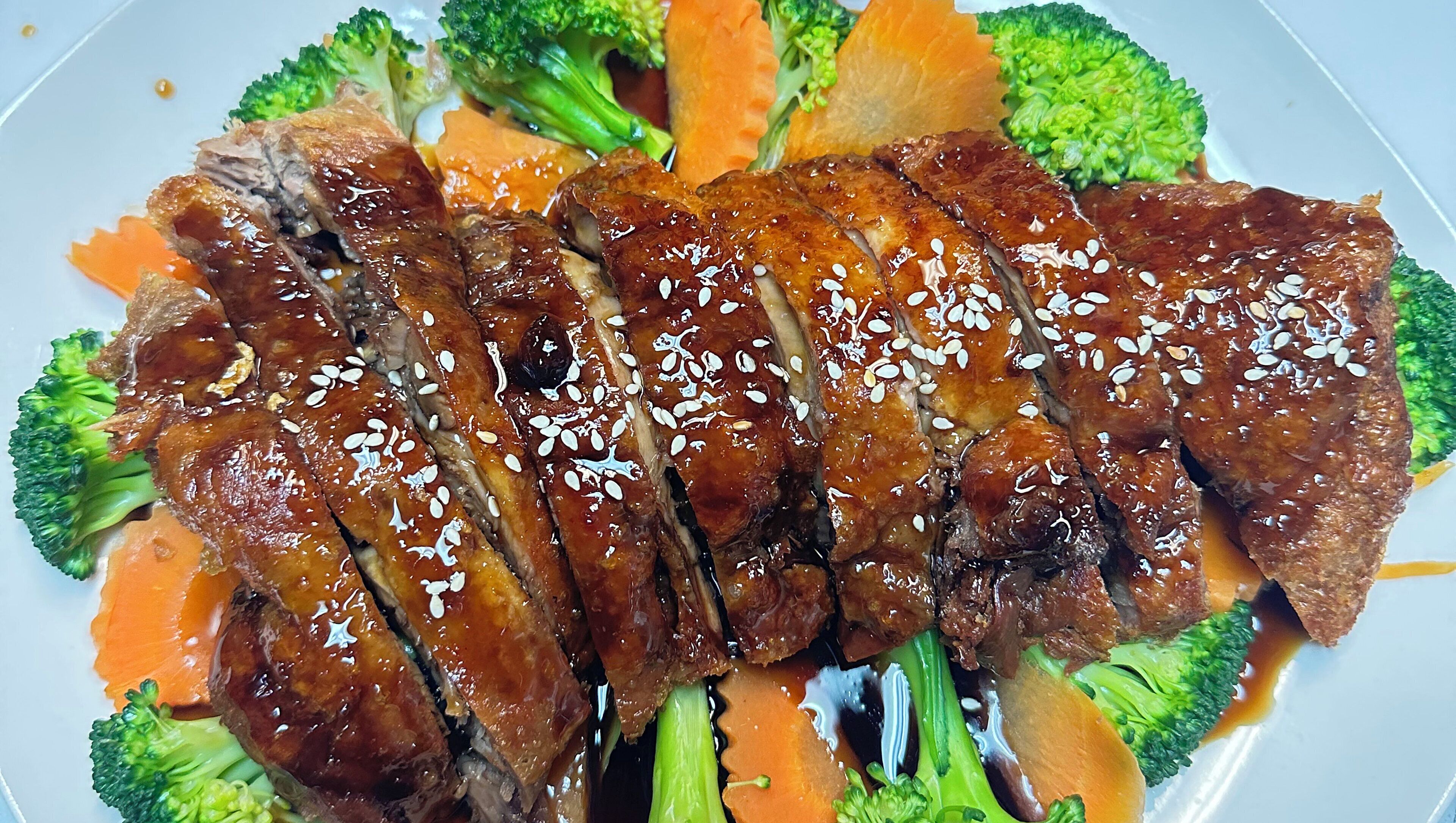 Un plato de carne en rodajas con semillas de sésamo y verduras.