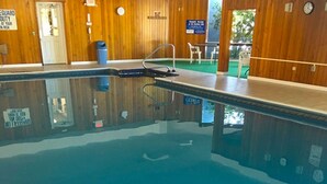 An indoor swimming pool with wooden walls, a lifeguard duty sign, and a welcome sign.