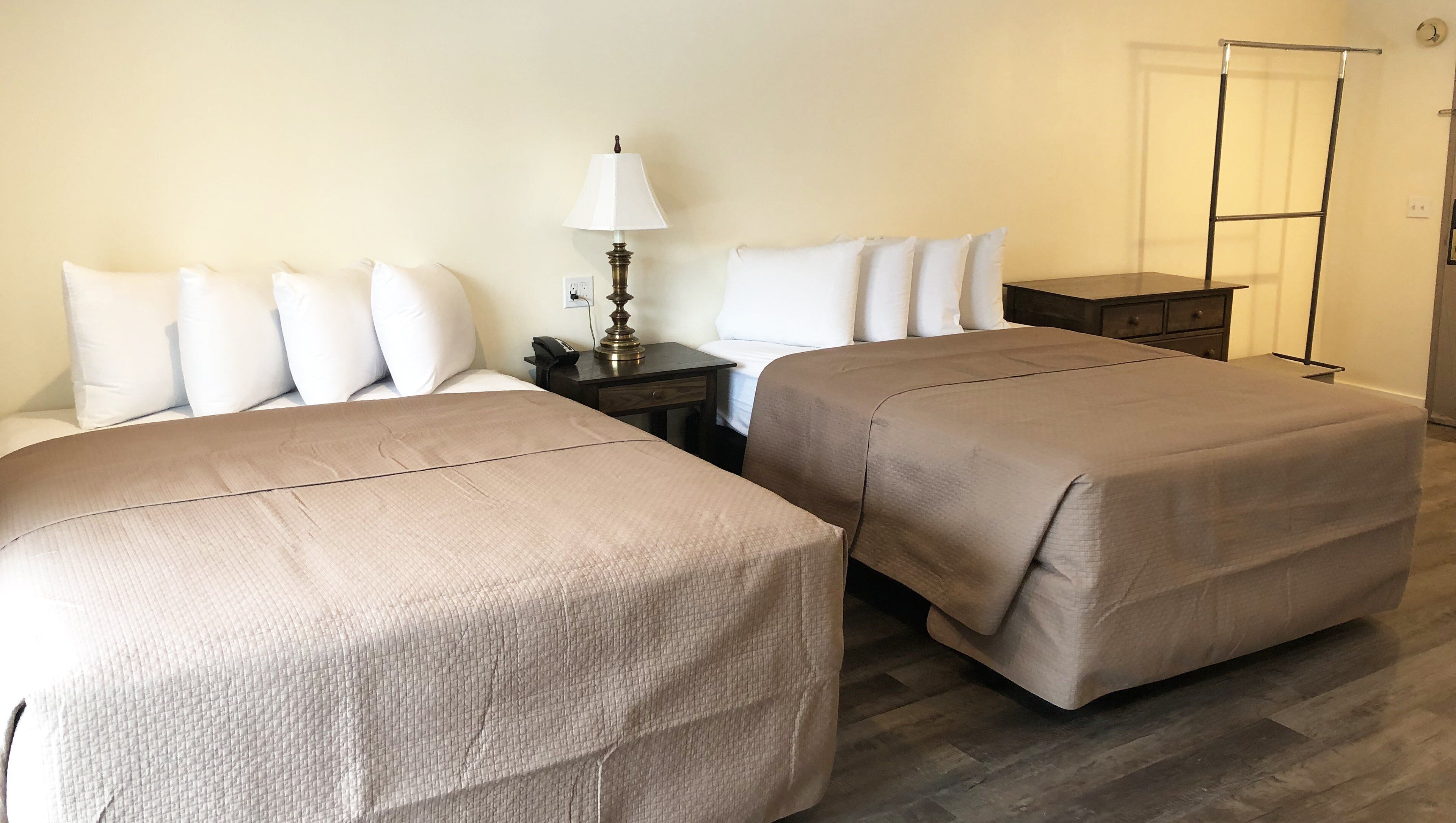 Une chambre d’hôtel avec deux lits, une table de chevet avec une lampe, une commode et un placard.