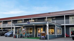 A motel with a covered entrance, outdoor seating, and a sign indicating an office.