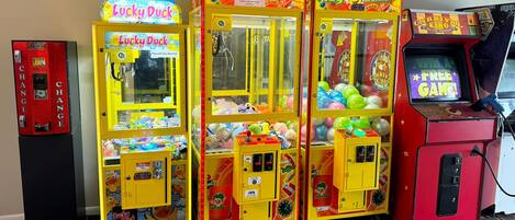 A row of claw machines with various themes, including Lucky Duck and Toy Soldier, in a brightly lit indoor setting.