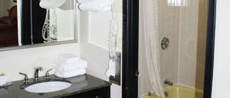A bathroom with a sink, mirror, and bathtub.