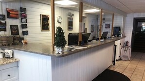 A reception desk with a computer, a clock, and various framed pictures on the wall.