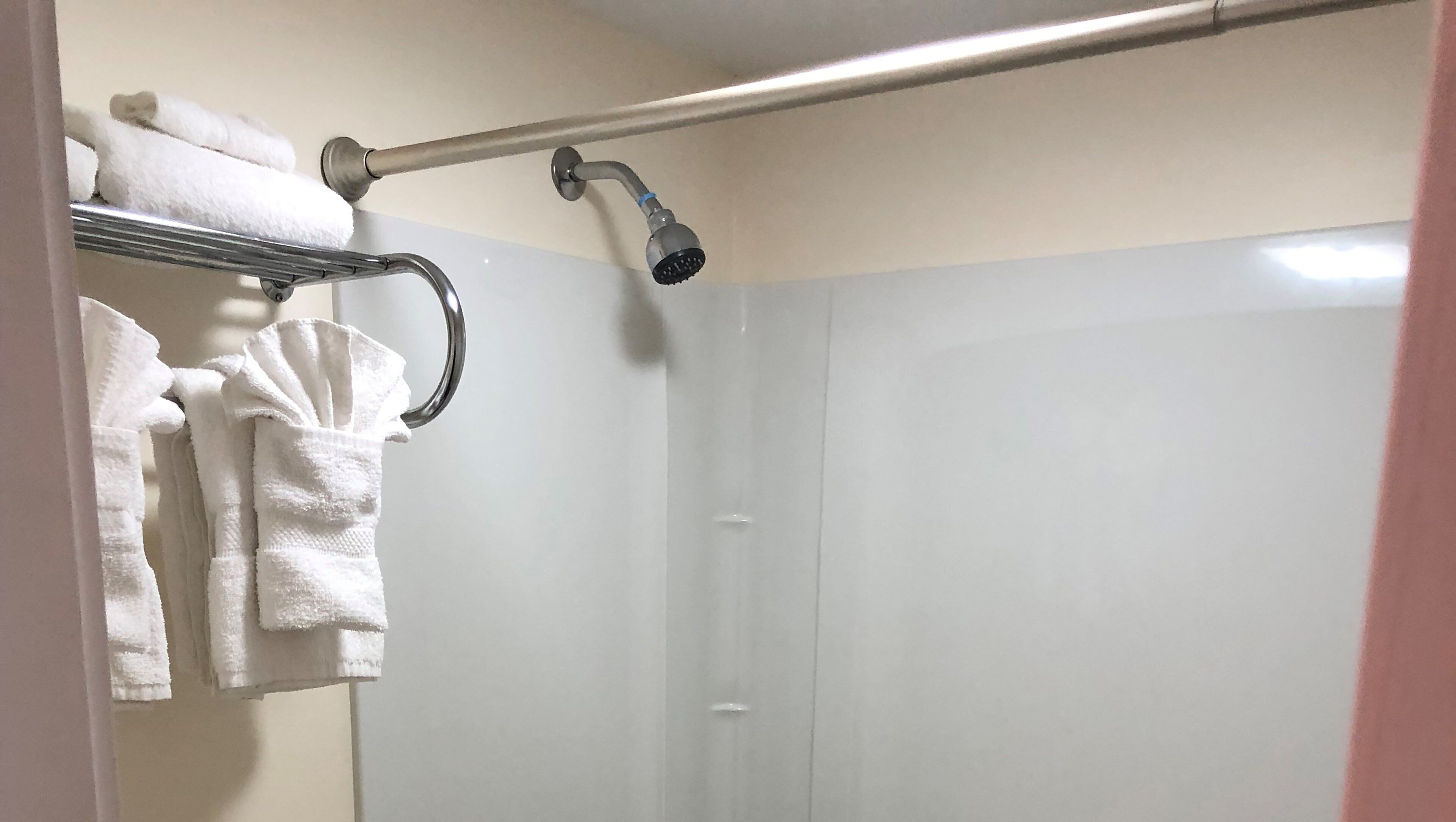 A bathroom with a shower, a towel rack with white towels, and a glass shower enclosure.