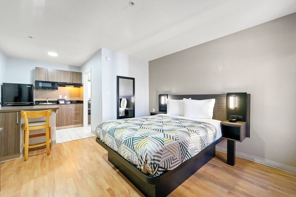A modern hotel room with a bed, bedside table, and a small desk area.