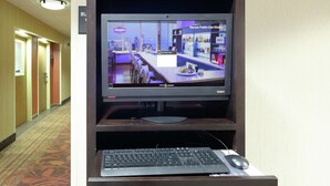 A hotel lobby with a monitor displaying a cityscape, a reception desk, and a carpeted floor.