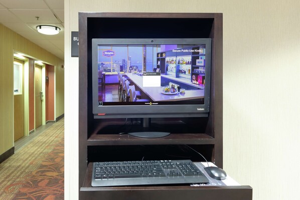 A hotel lobby with a monitor displaying a cityscape, a reception desk, and a carpeted floor.