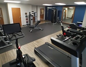 Un gimnasio con cintas de correr, una bicicleta estática y una máquina de pesas.