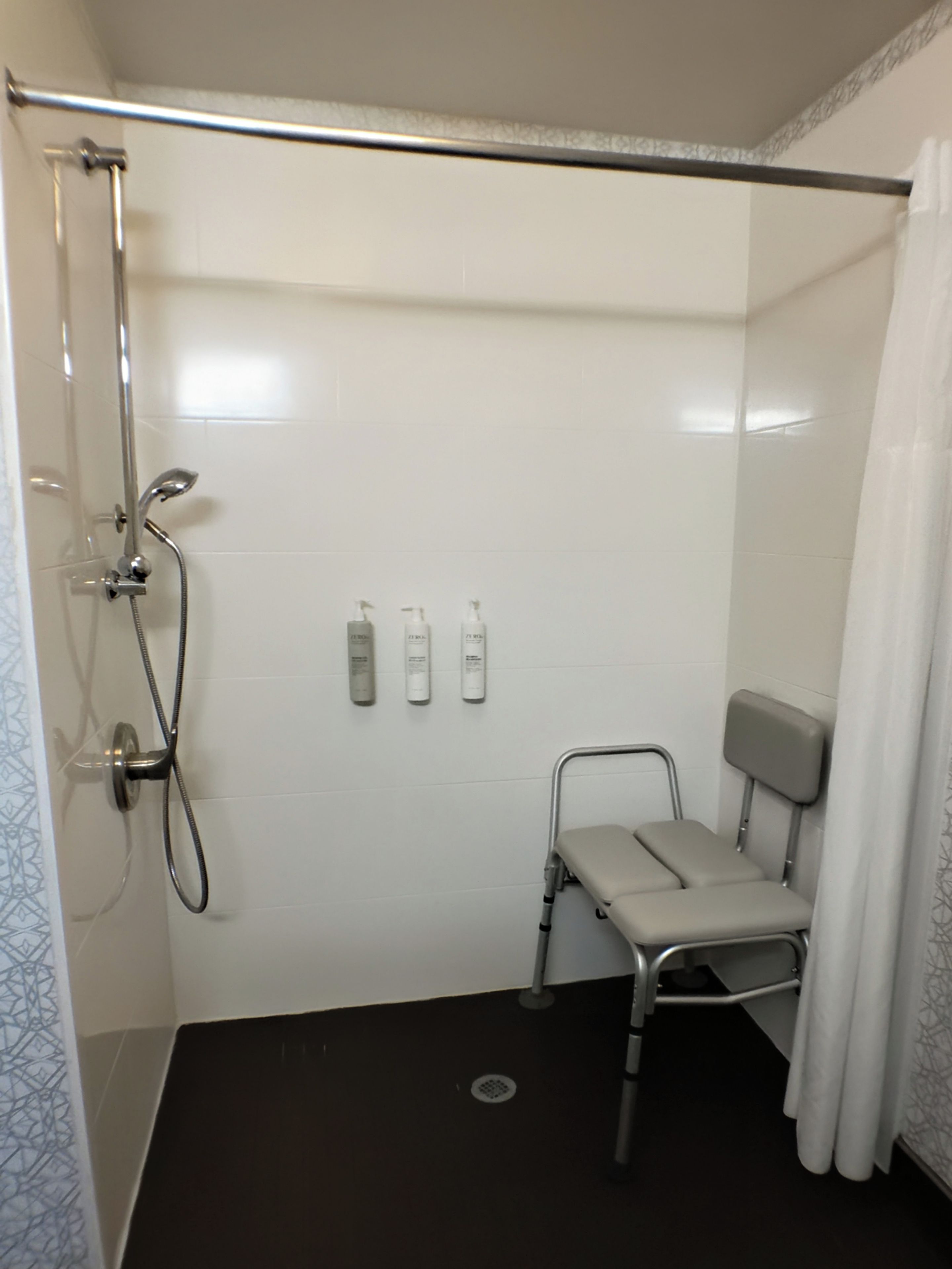 A shower area with a showerhead, handheld shower, and a wall-mounted soap dispenser.